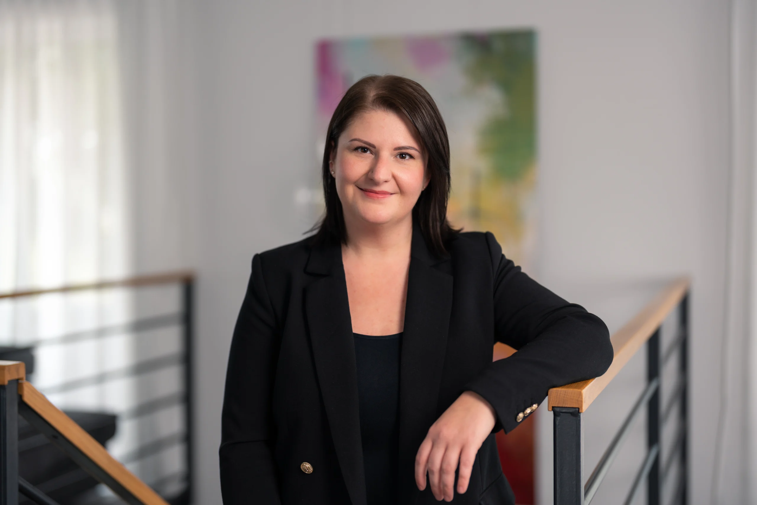 Sympathische Social Media Managerin aus Borchen-Etteln, seriös gekleidet am Treppengeländer